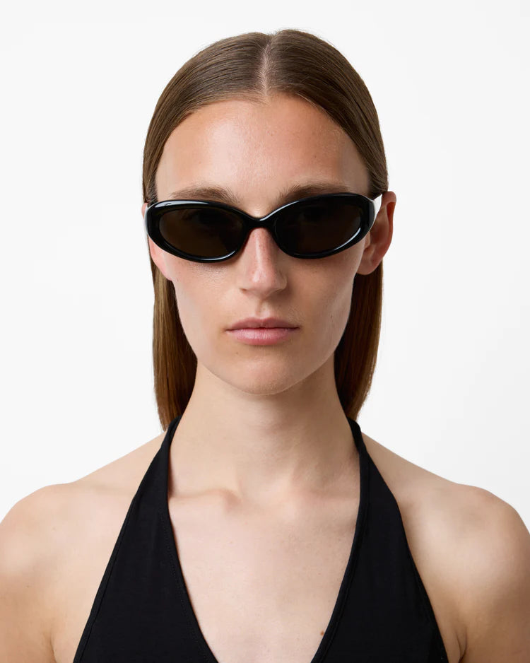 Woman wearing black sunglasses and a black halter top on a white background