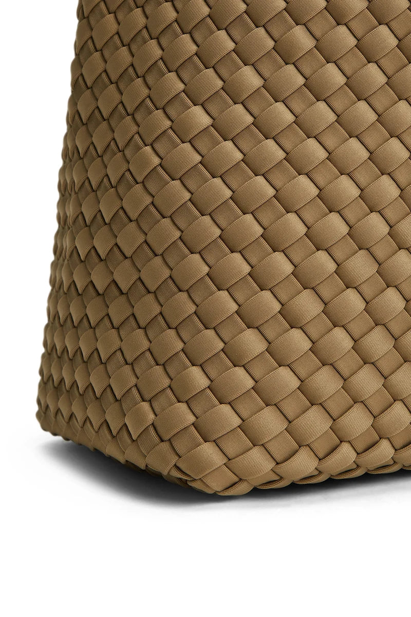 Close-up of a woven leather bag corner in a warm tan-brown color, showing the detailed basketweave texture against a white background.