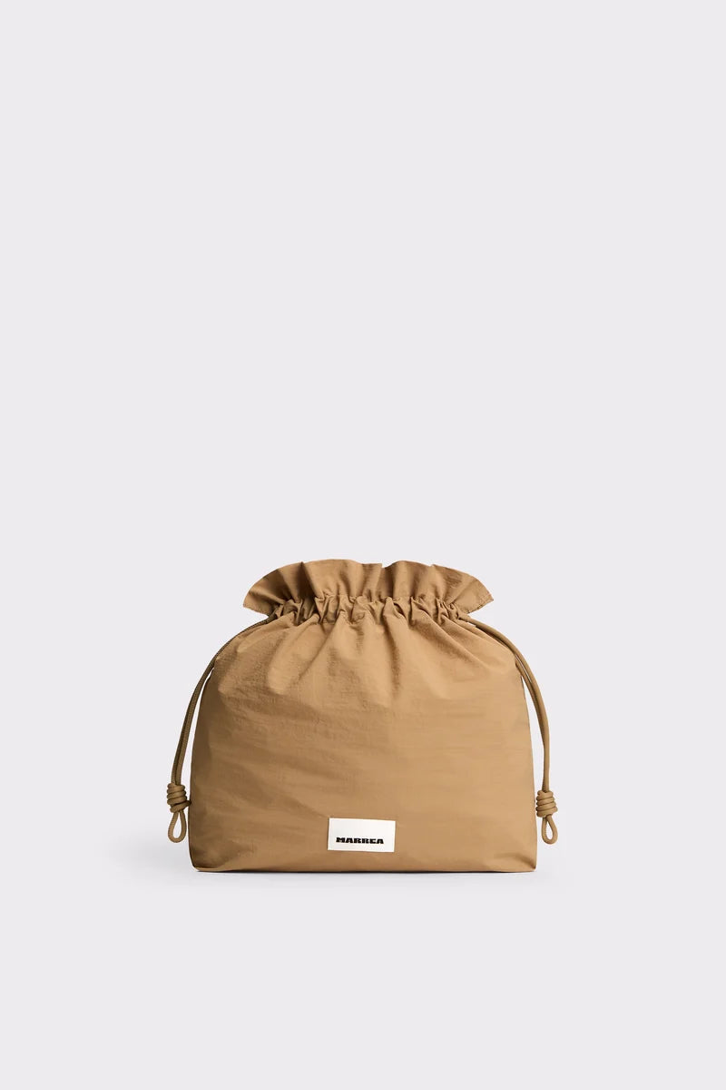 A tan drawstring dust bag with a small white rectangular label reading 'MADEIRA' on the front, set against a solid light gray background.