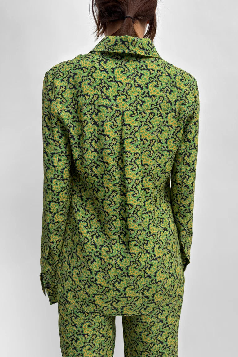 A model shown from the back wearing a matching green and yellow patterned long-sleeve top and trousers set against a light gray studio background.