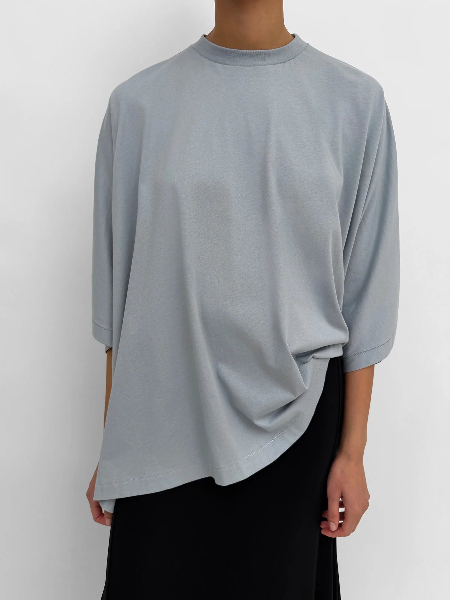Person wearing a light gray long-sleeve top on a white background