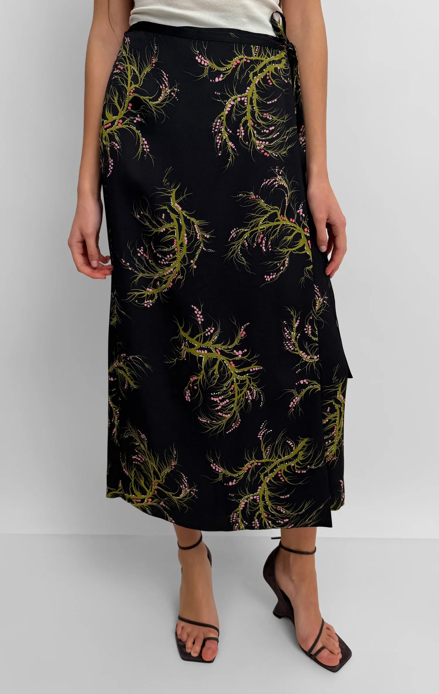 Black skirt with green leaf pattern worn by a person on a white background