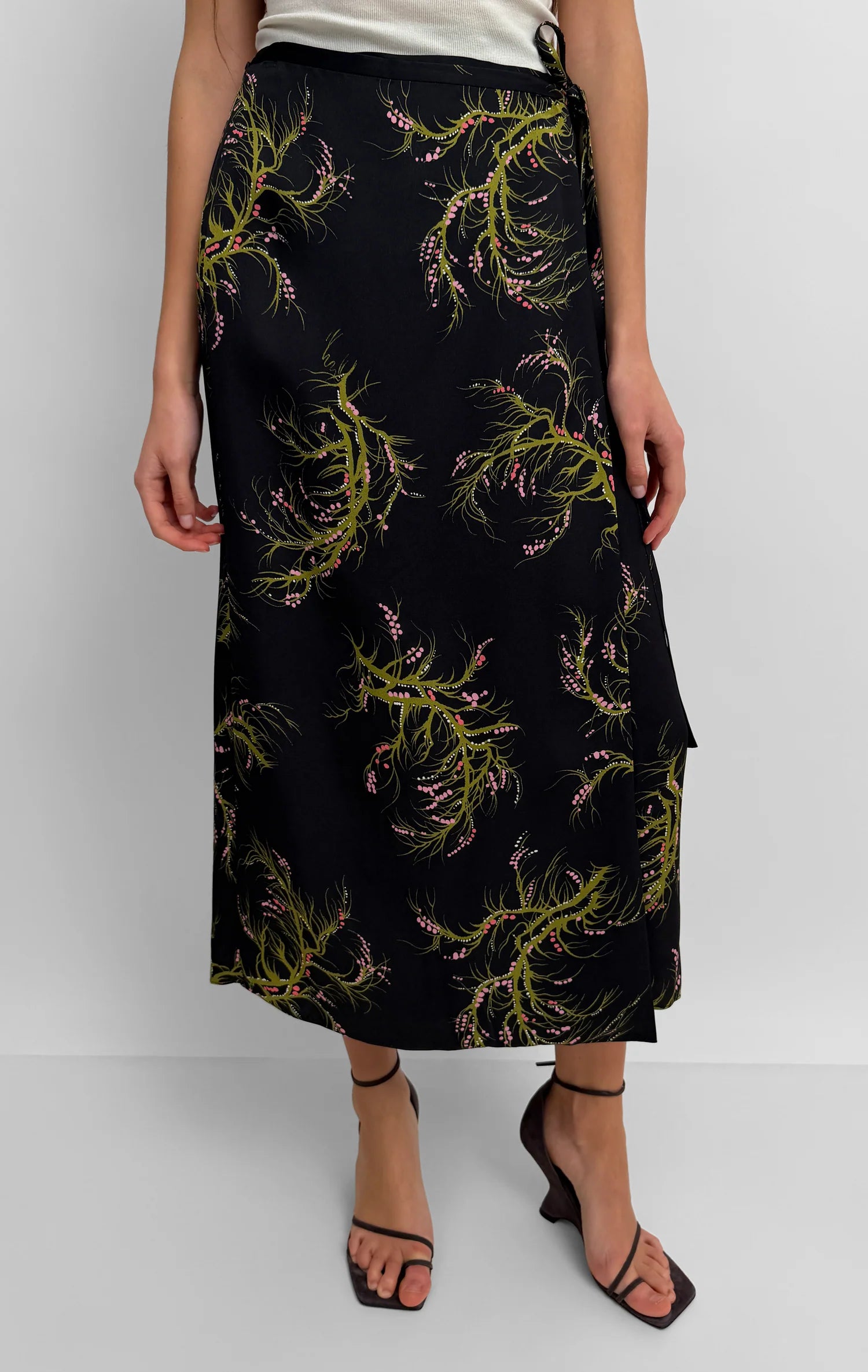 Black skirt with green leaf pattern worn by a person on a white background