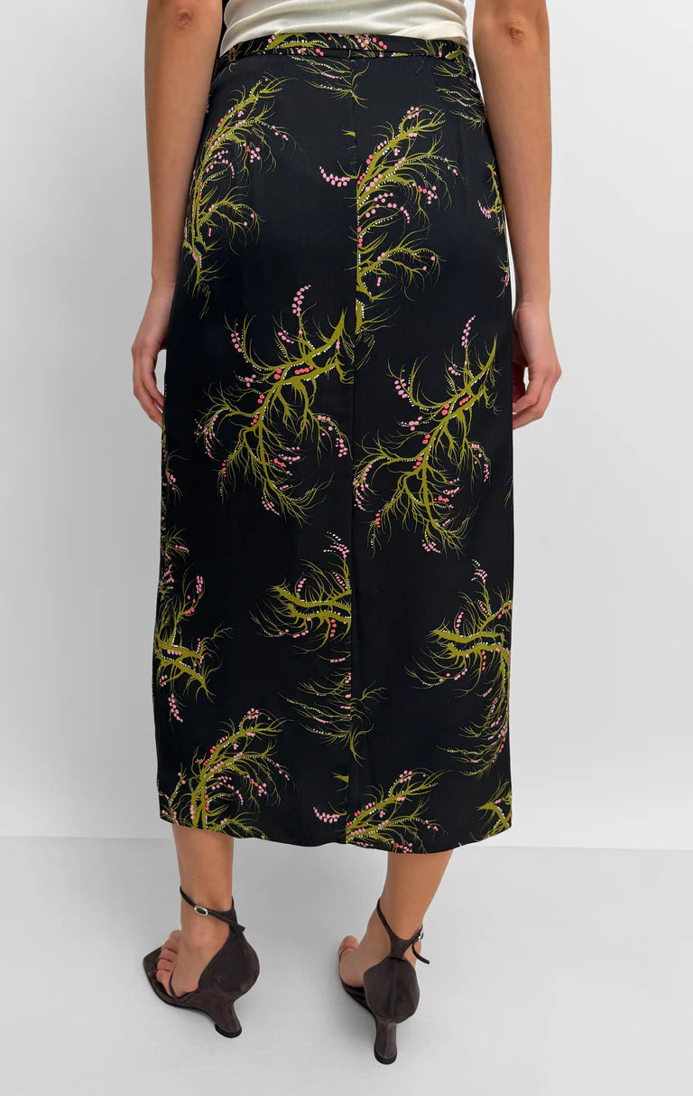 Person wearing a black skirt with green floral pattern on a white background