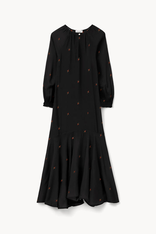 A black long-sleeve midi dress with a small orange embroidered pattern, featuring a gathered neckline and a flared ruffled hem, shown against a plain off-white background.