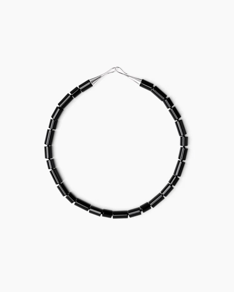 A black beaded necklace with silver-toned metal connectors, arranged in a circular shape against a plain white background.