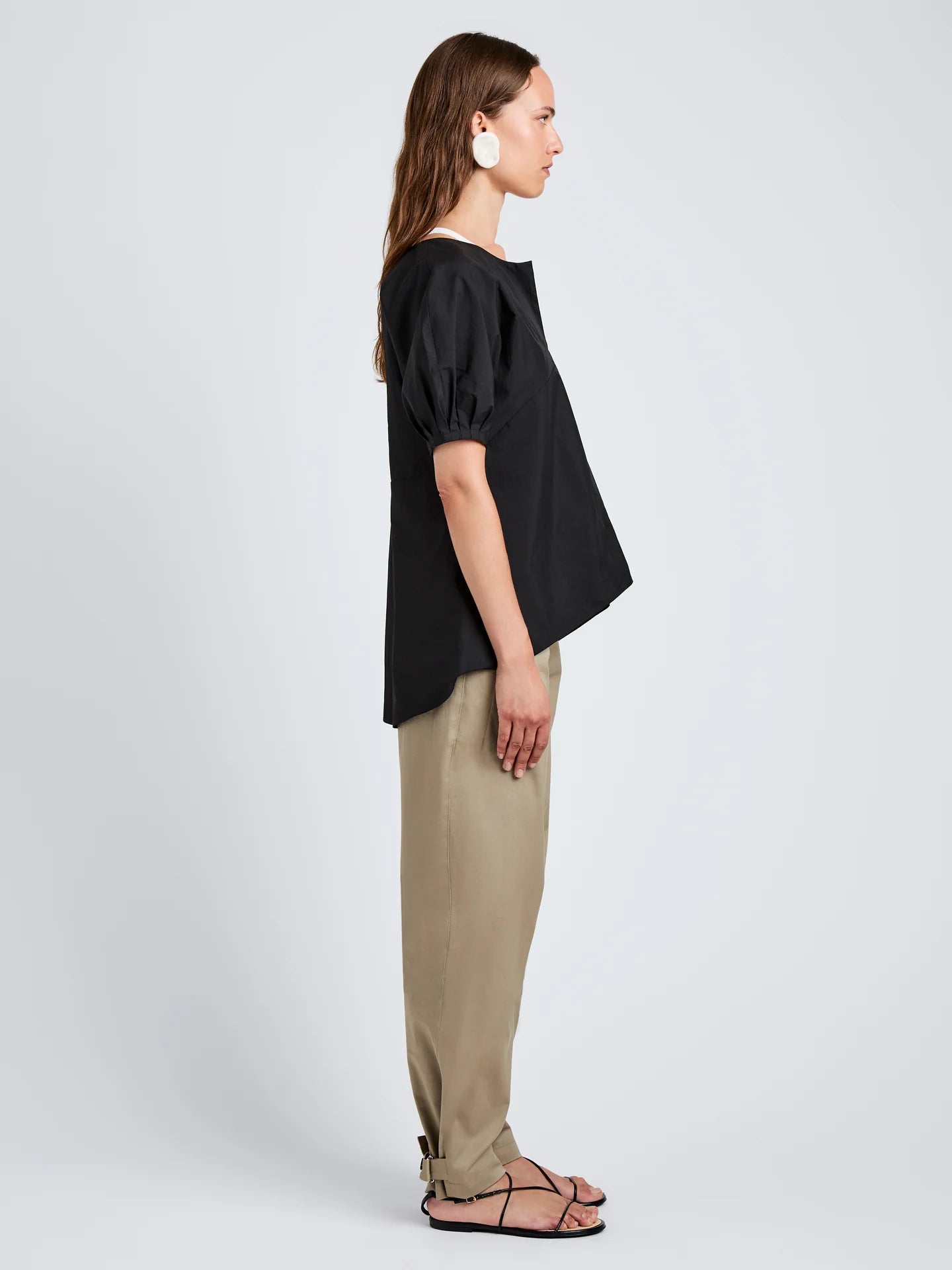 Woman wearing a black top and beige pants on a white background