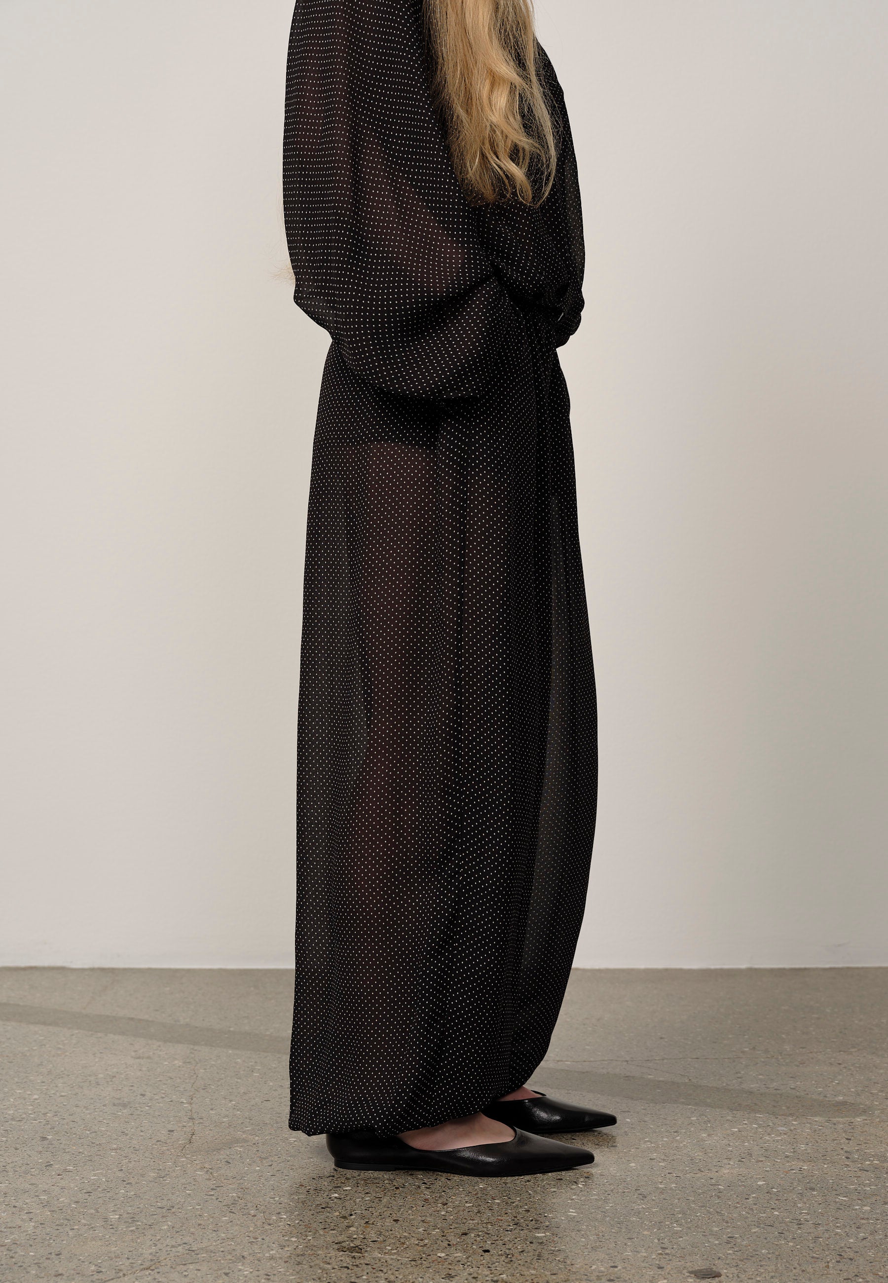 Person wearing a long black dress with a white background