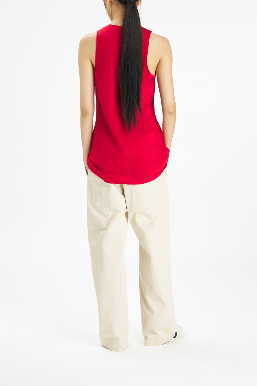 A woman shown from the back wearing a bright red sleeveless top and cream-colored wide-leg pants against a plain white studio background.