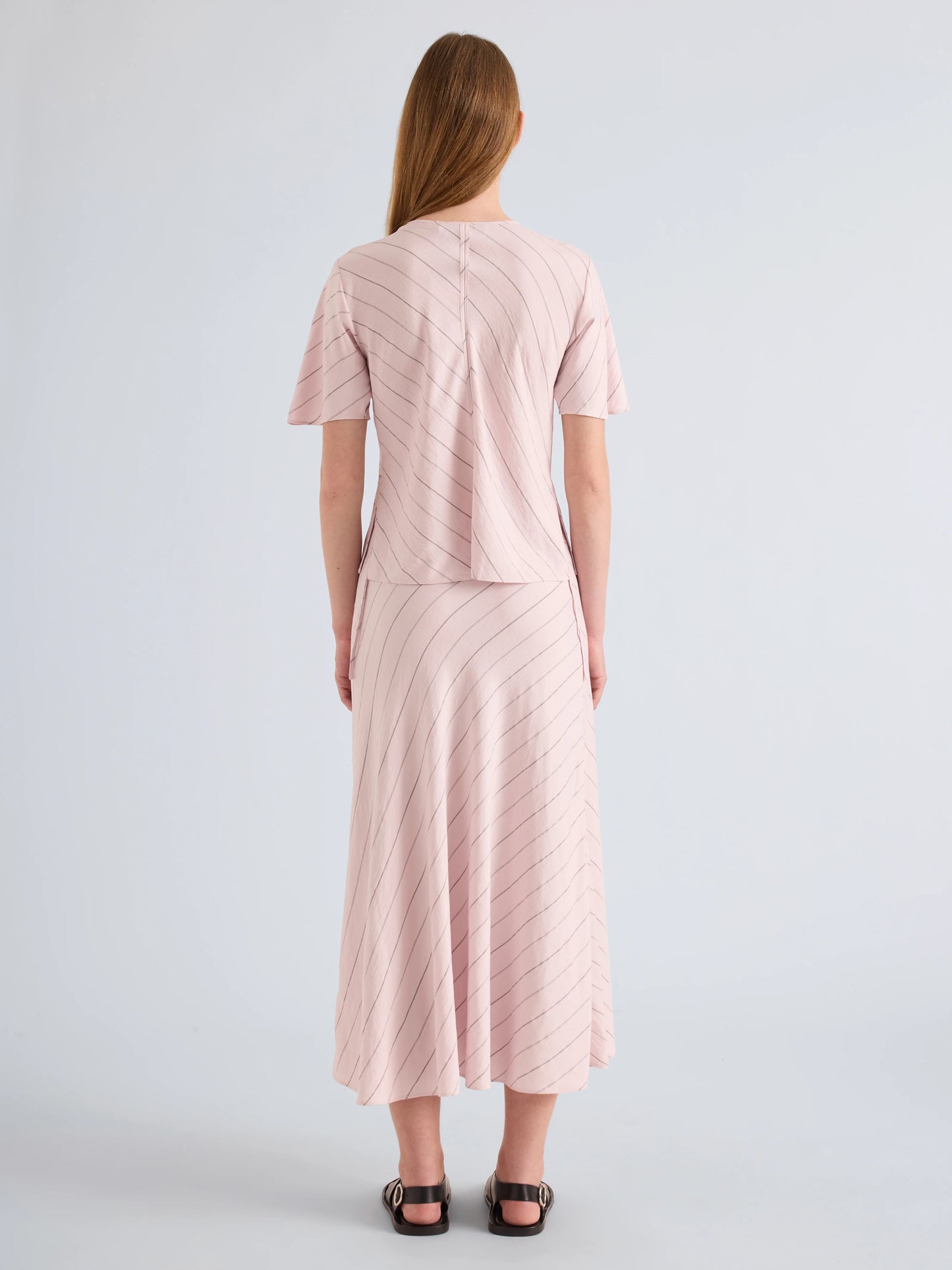 Woman wearing a light pink dress with a subtle pattern on a plain background