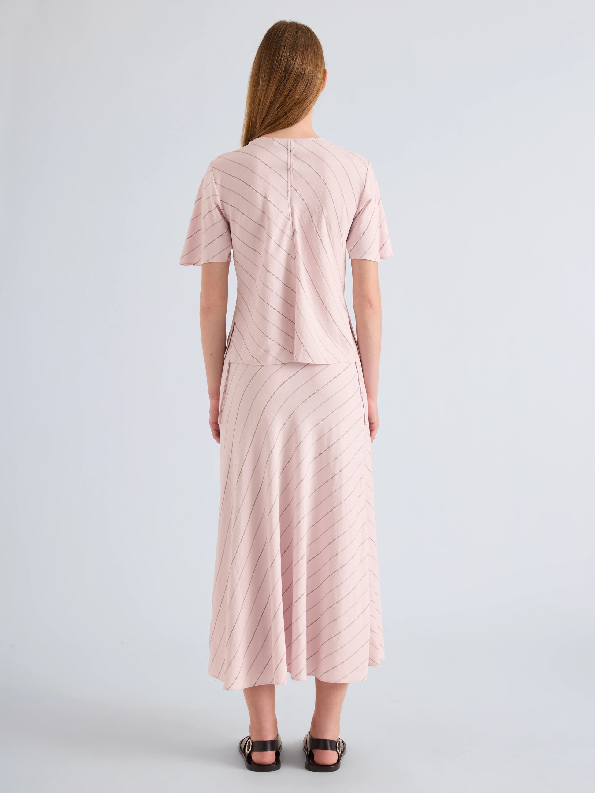 Woman wearing a light pink dress with a subtle pattern on a plain background