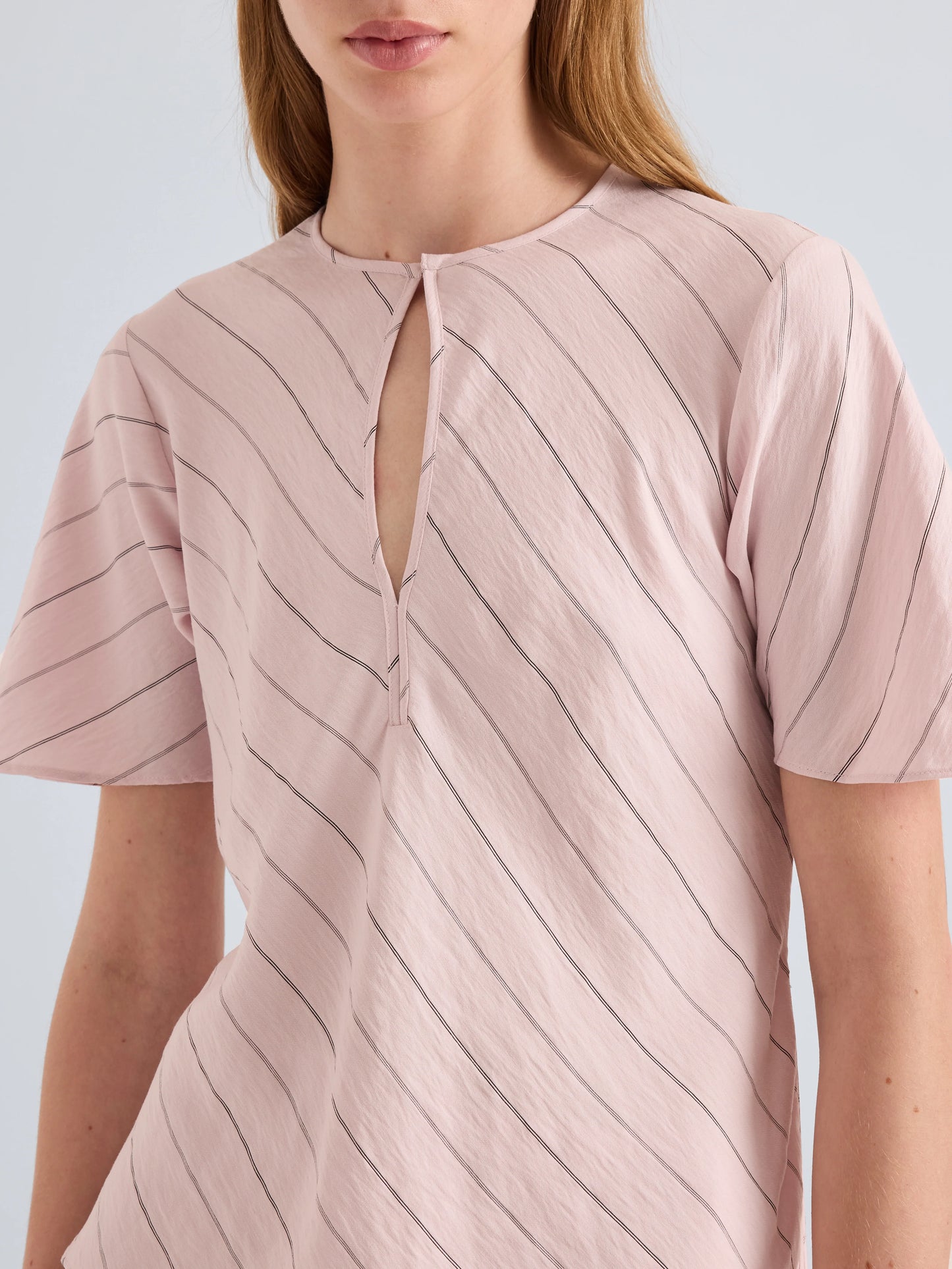 Pink striped shirt worn by a person on a light gray background