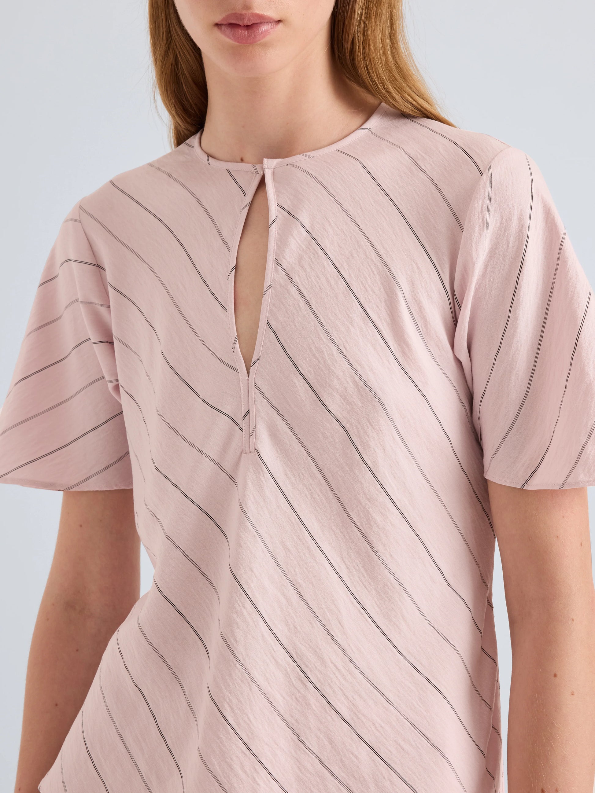 Pink striped shirt worn by a person on a light gray background