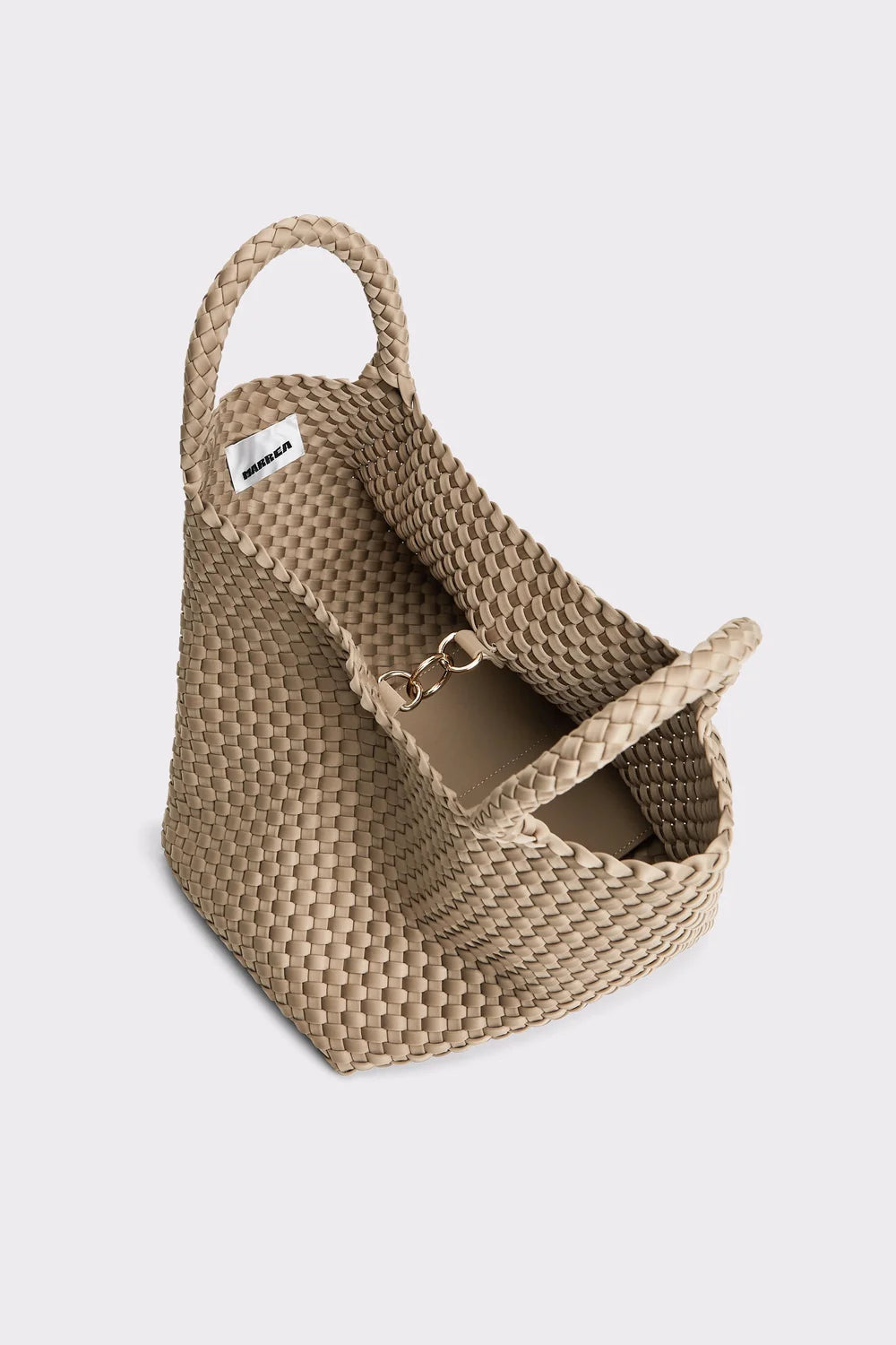 A woven straw tote bag in a natural beige color, featuring dual top handles and a small white brand tag on the side, photographed on a light gray background.