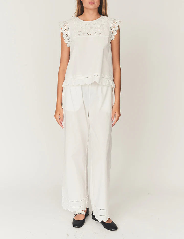Person wearing a white outfit with lace details on a plain background