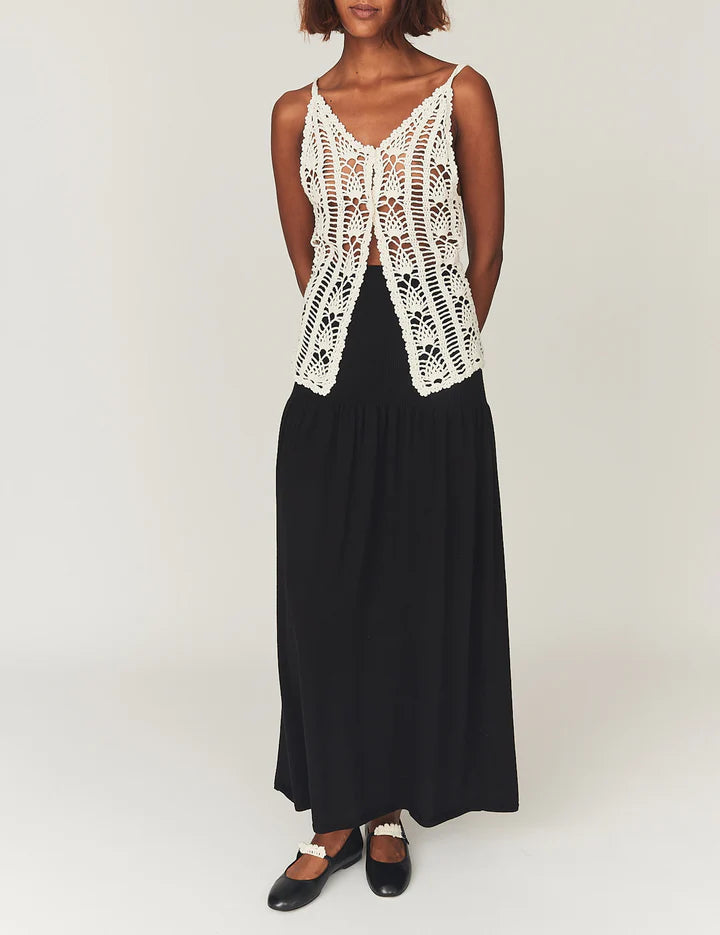 Person wearing a white lace top and black skirt on a white background