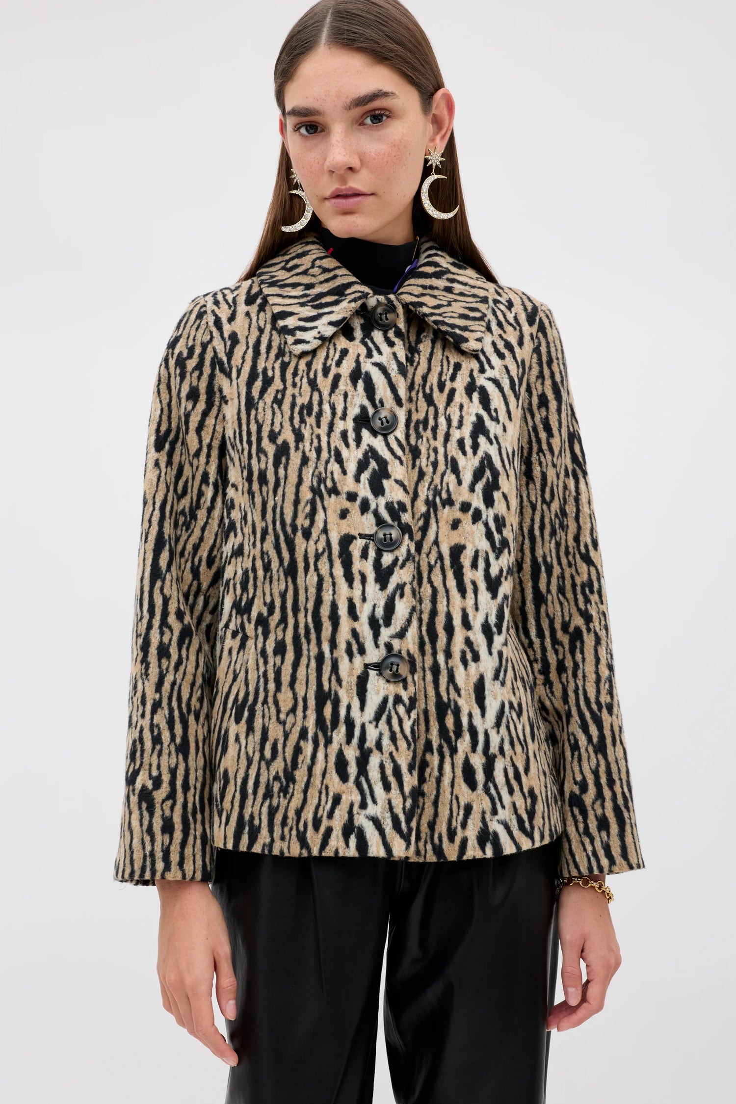 A model wearing a beige and black leopard-print cropped jacket with a wide collar and front buttons, paired with black pants, against a plain light gray background.