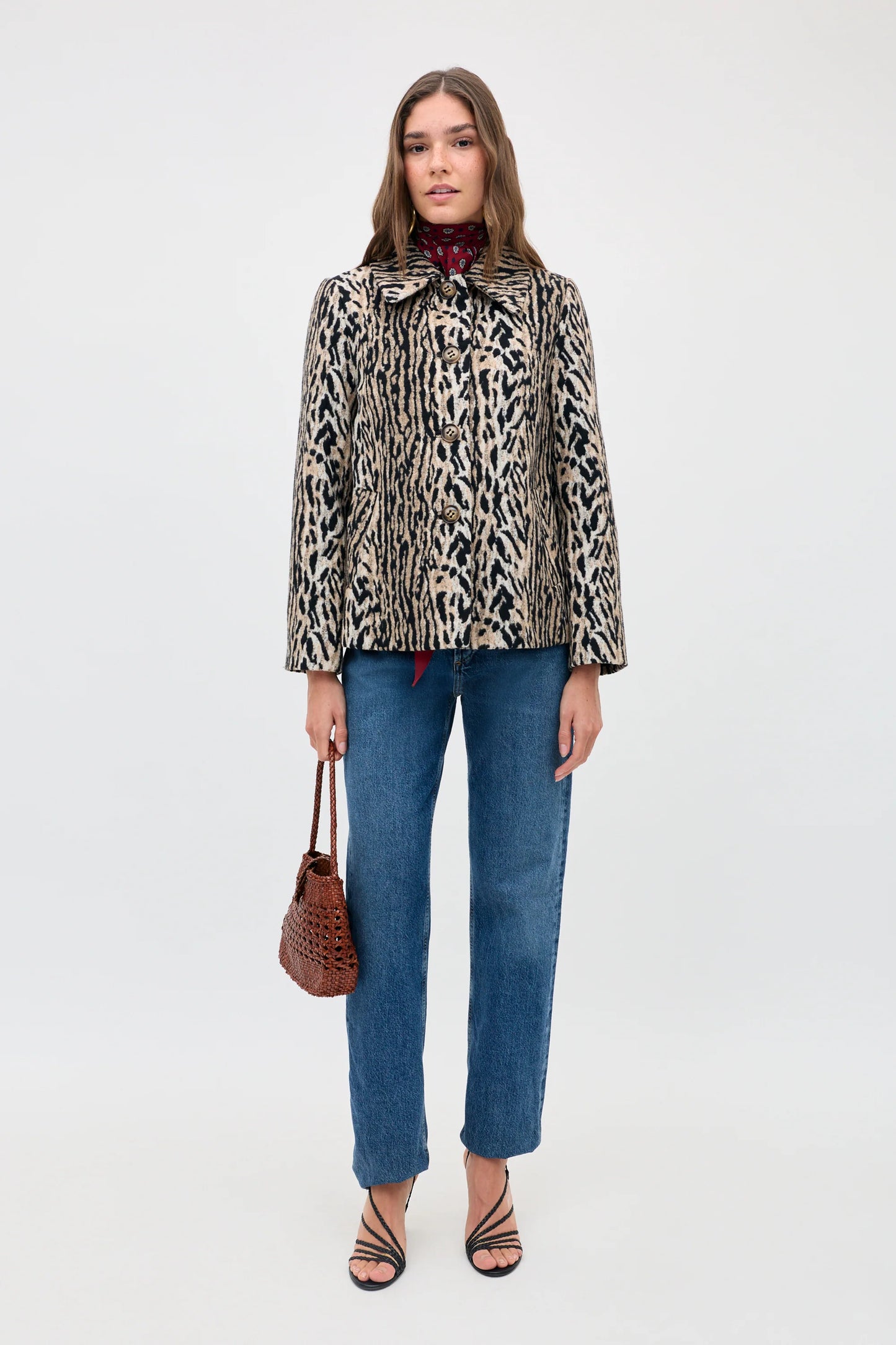 Woman wearing a leopard print jacket and blue jeans on a white background