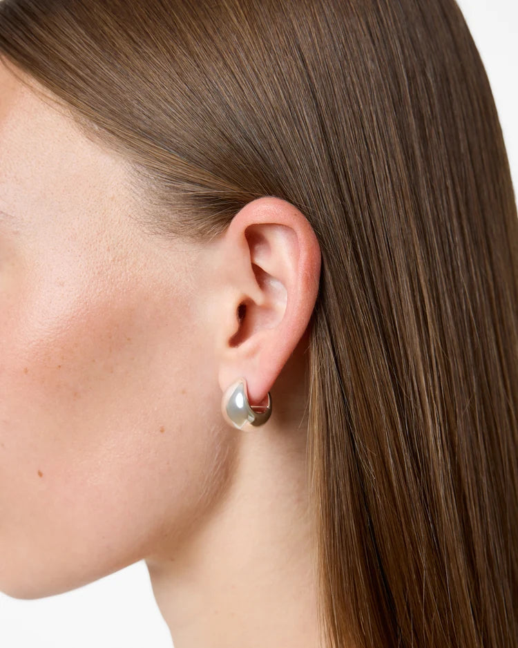Close-up of a person wearing a silver earring with a pearl center.