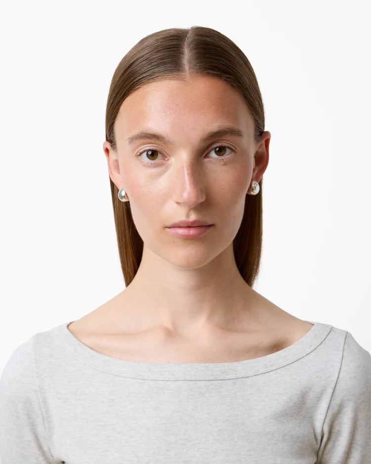 Woman wearing a light gray top against a white background