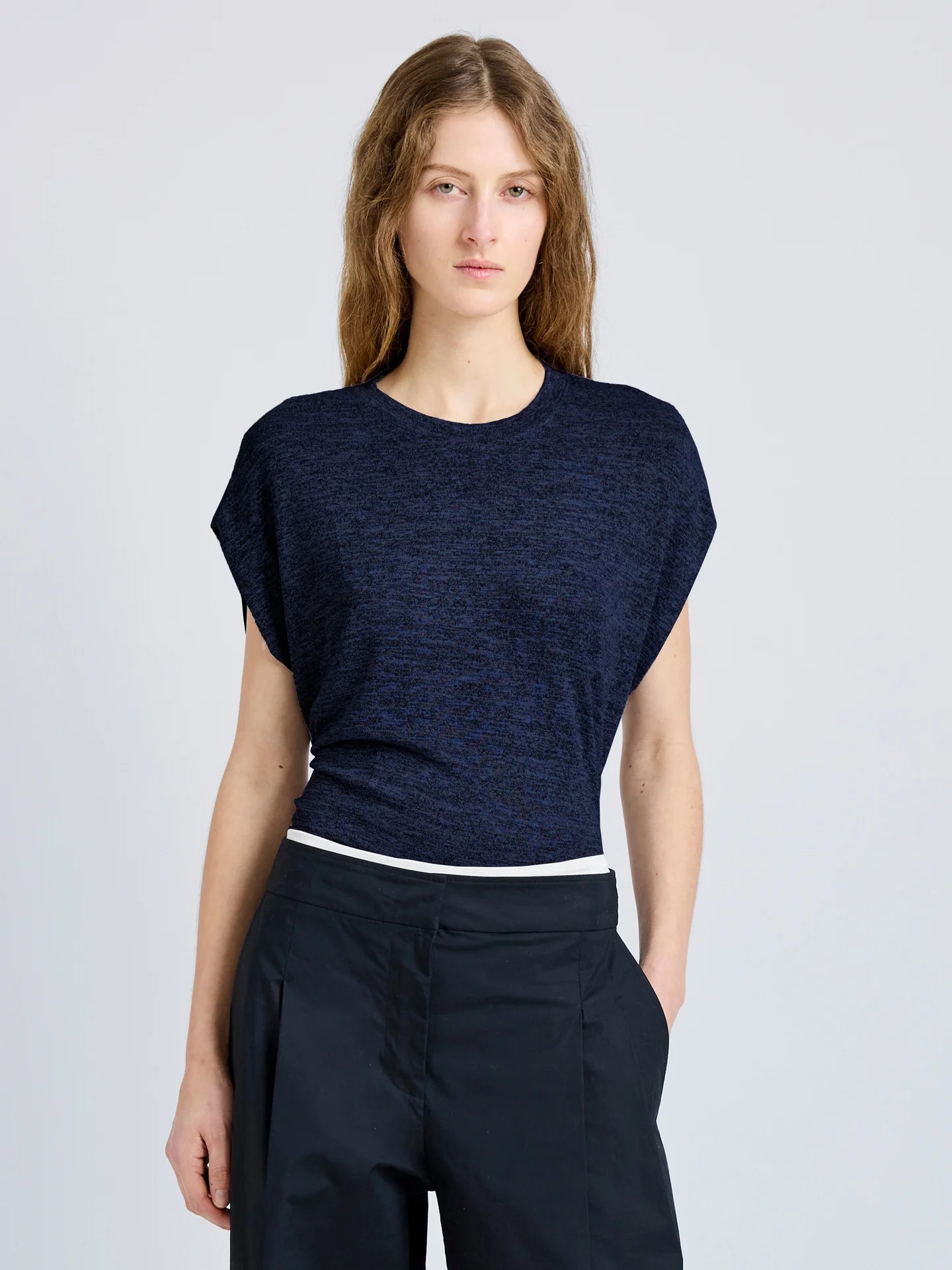 Woman wearing a navy blue top  on a light gray background