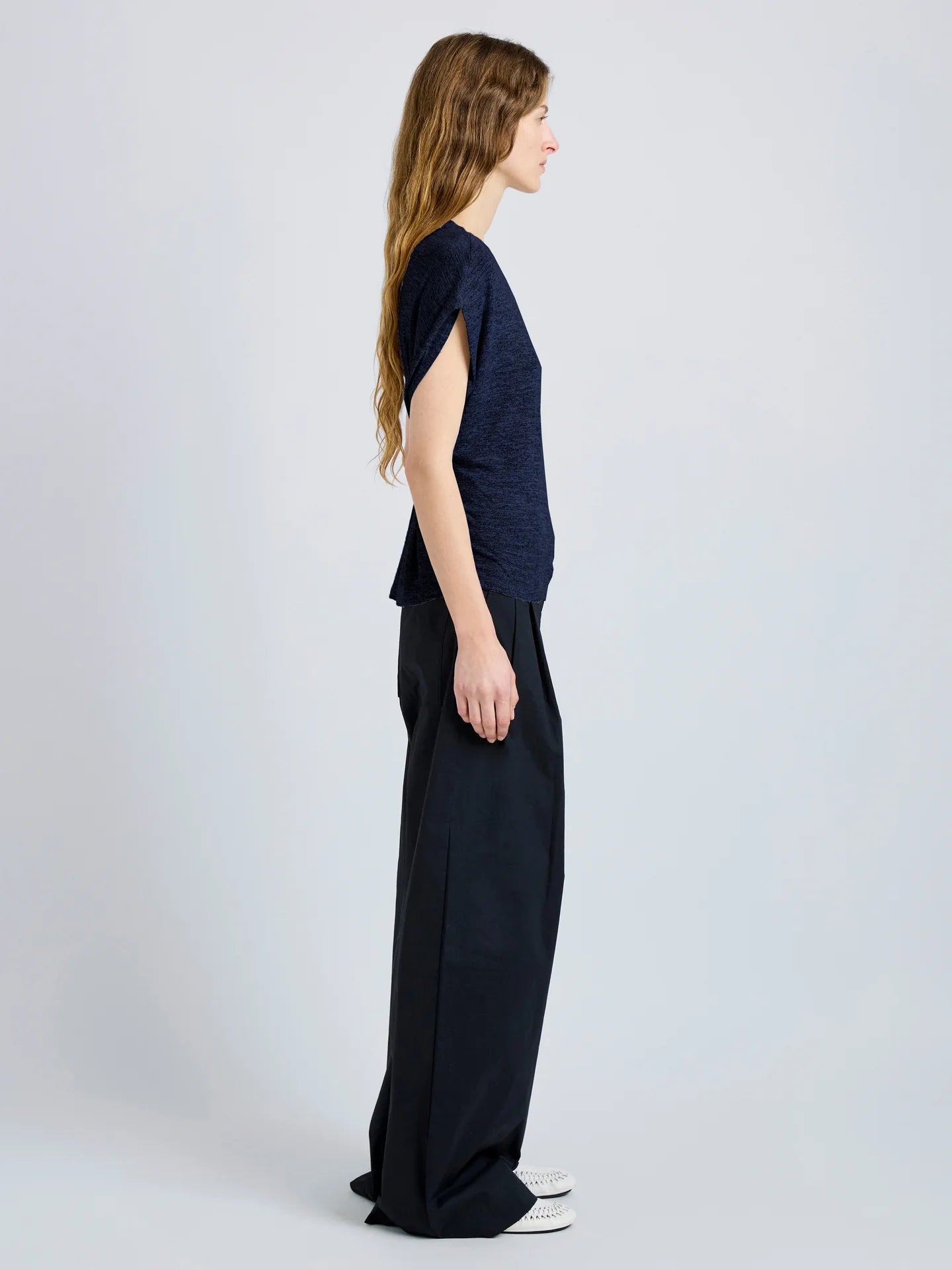 Woman wearing a navy blue top and wide-leg pants on a light gray background