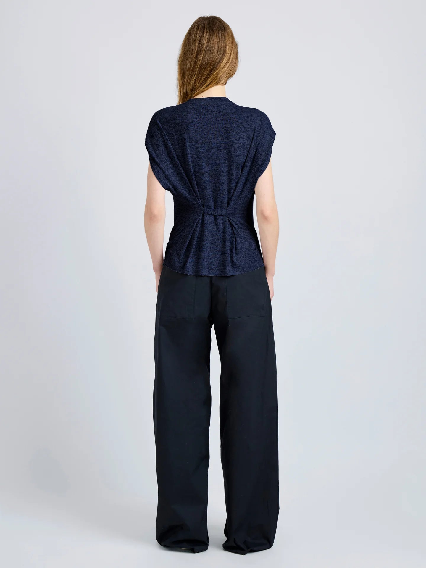 Woman wearing a navy blue top and wide-leg pants on a white background