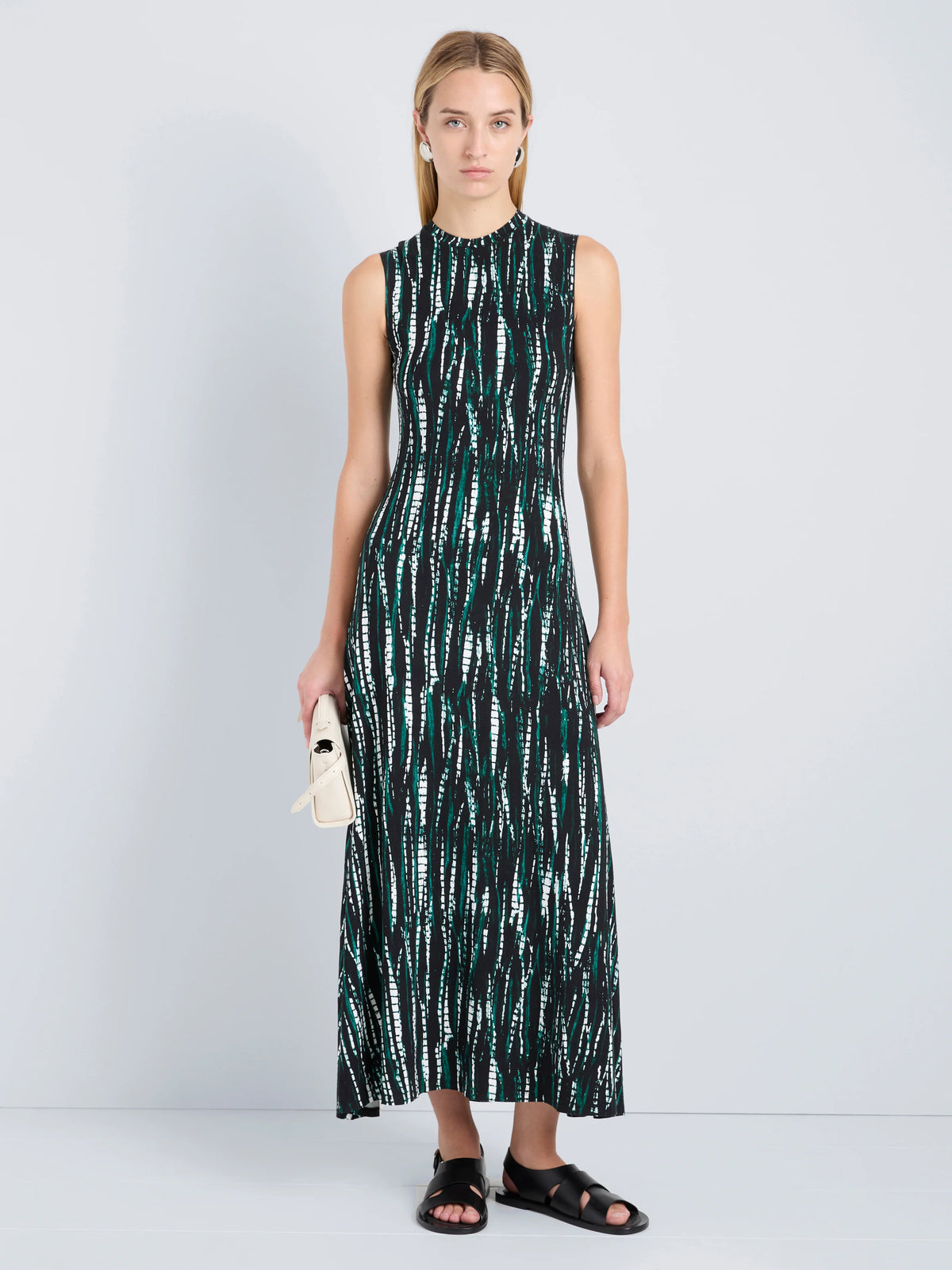 Woman wearing a sleeveless dress with a green and white pattern on a white background