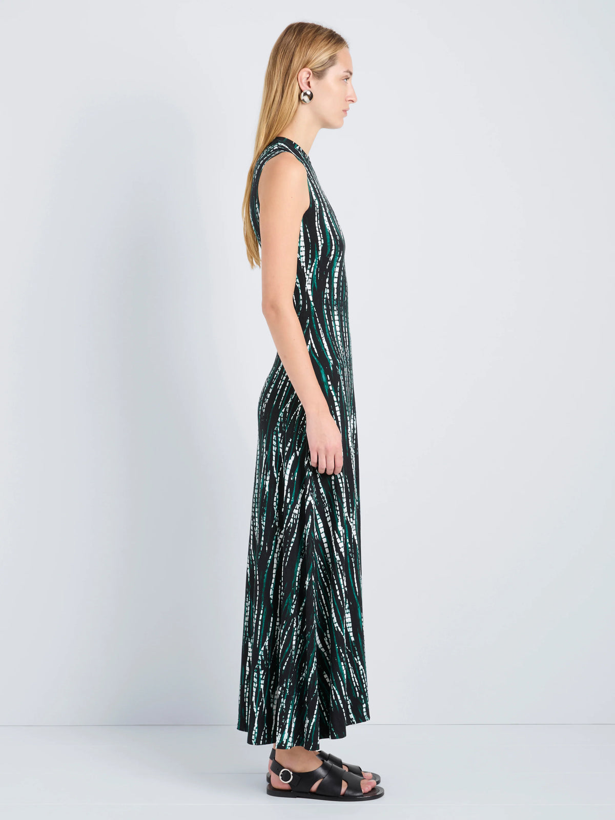 Woman wearing a sleeveless dress with a black and green pattern on a white background