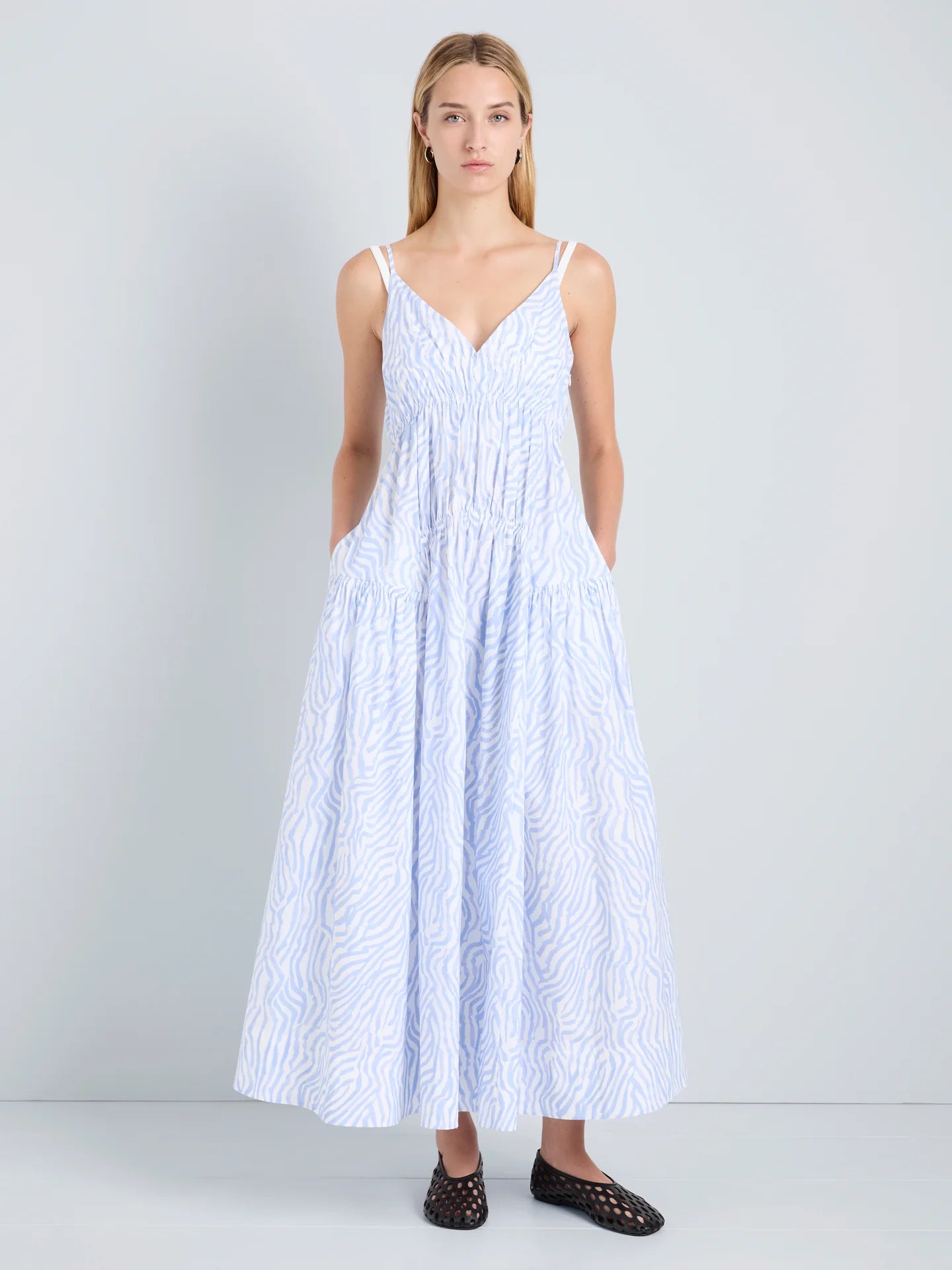 Woman wearing a white dress with blue patterns on a plain background