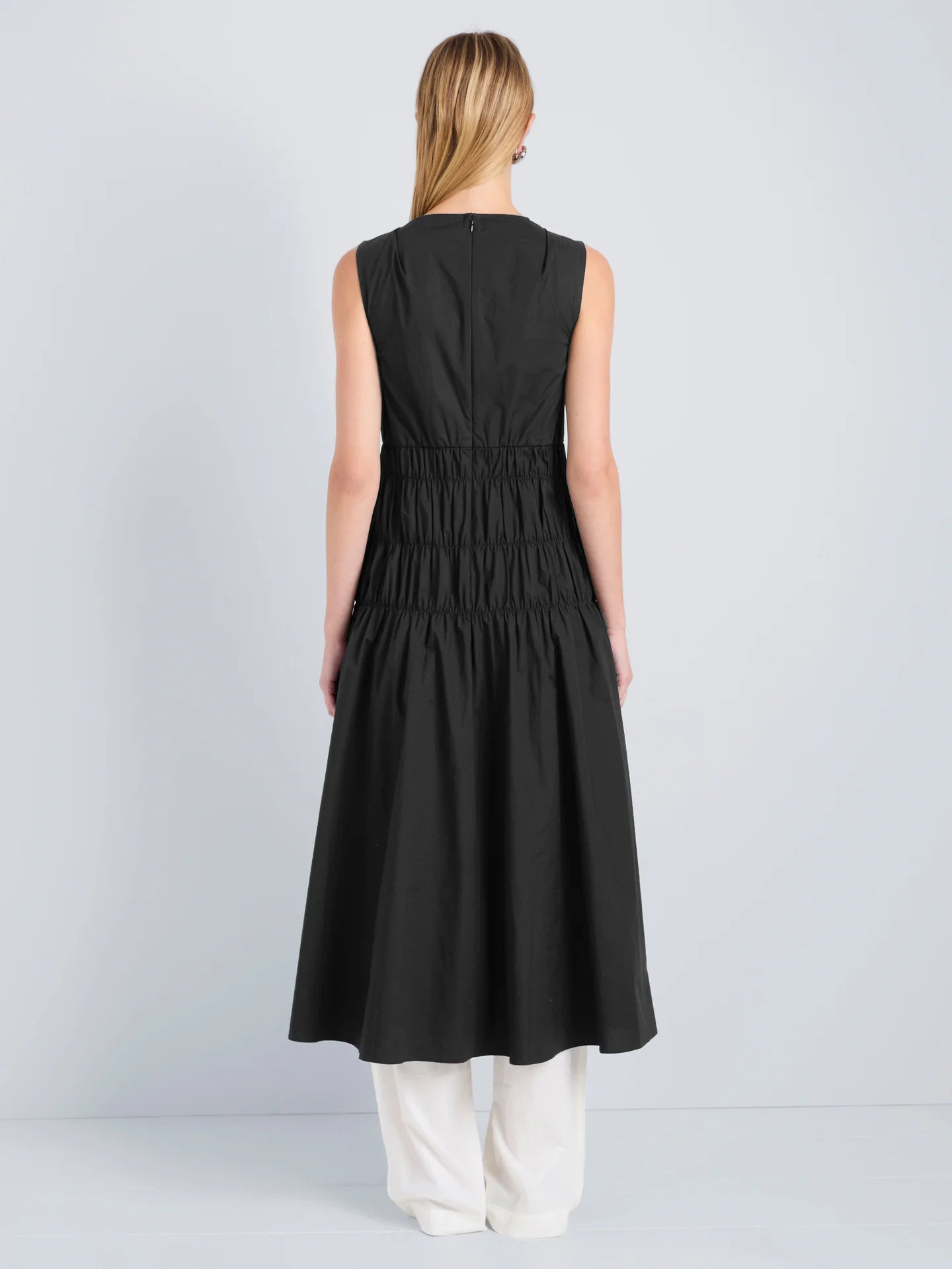 Woman wearing a black sleeveless dress on a light gray background
