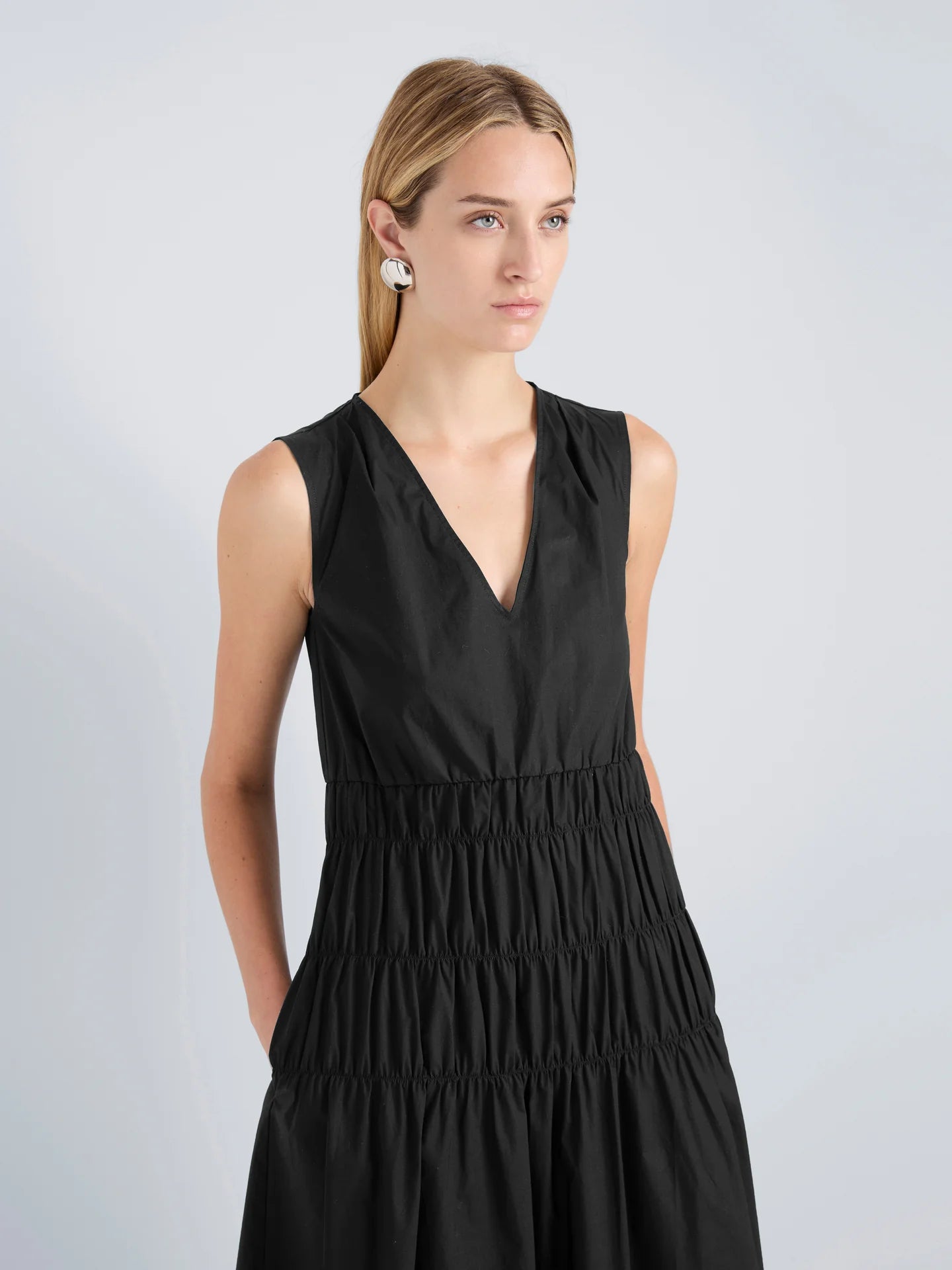 Woman wearing a black sleeveless dress against a light gray background
