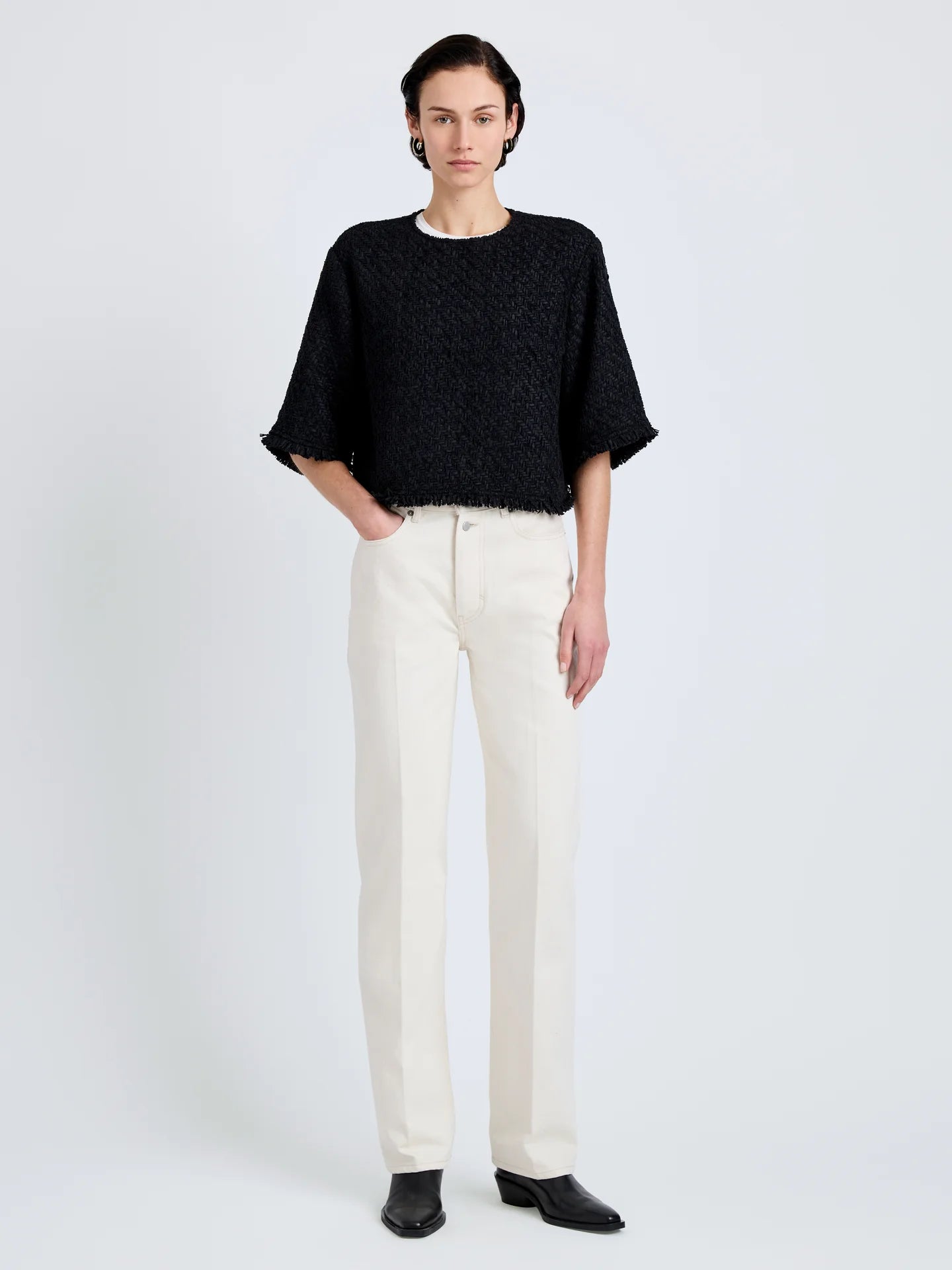 Person wearing a black top and white pants on a white background