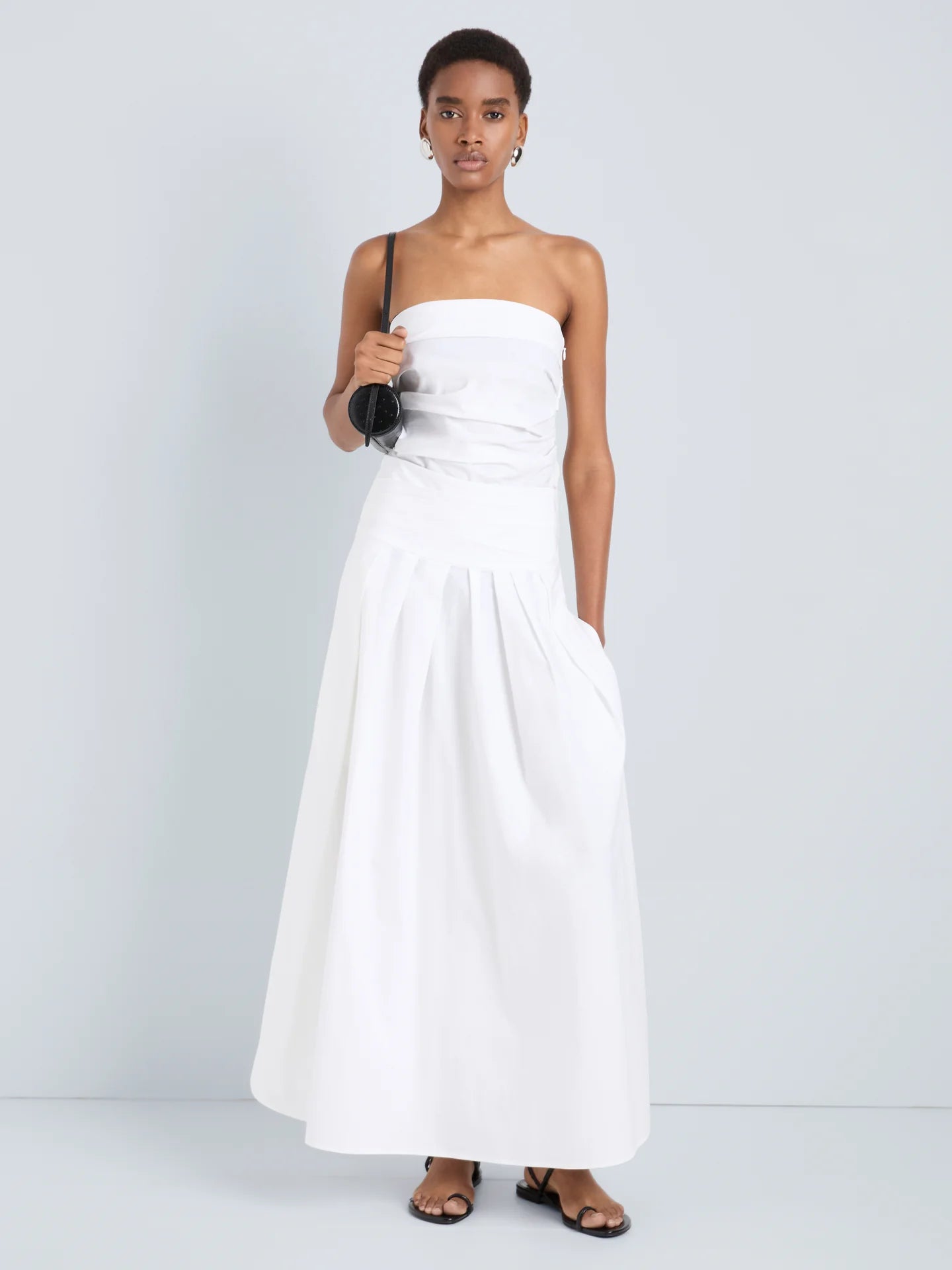 Woman wearing a white strapless dress against a plain background
