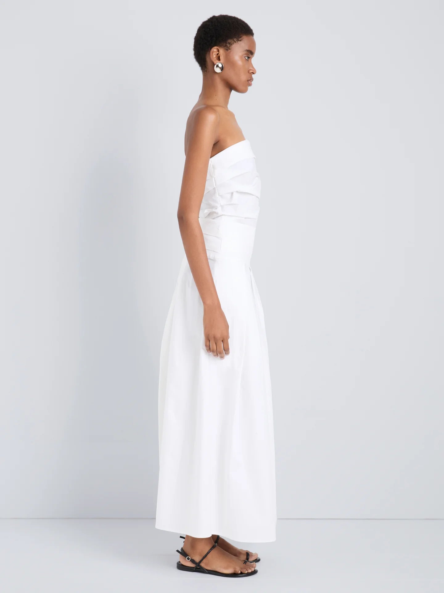 Woman wearing a white strapless dress on a plain background