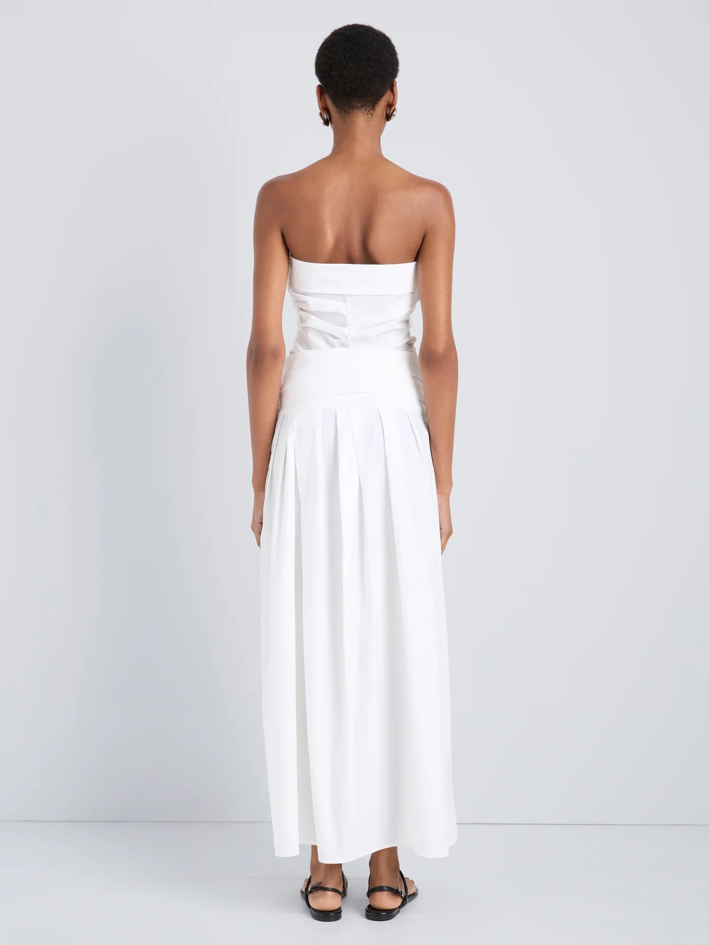 Woman wearing a strapless white dress against a plain background