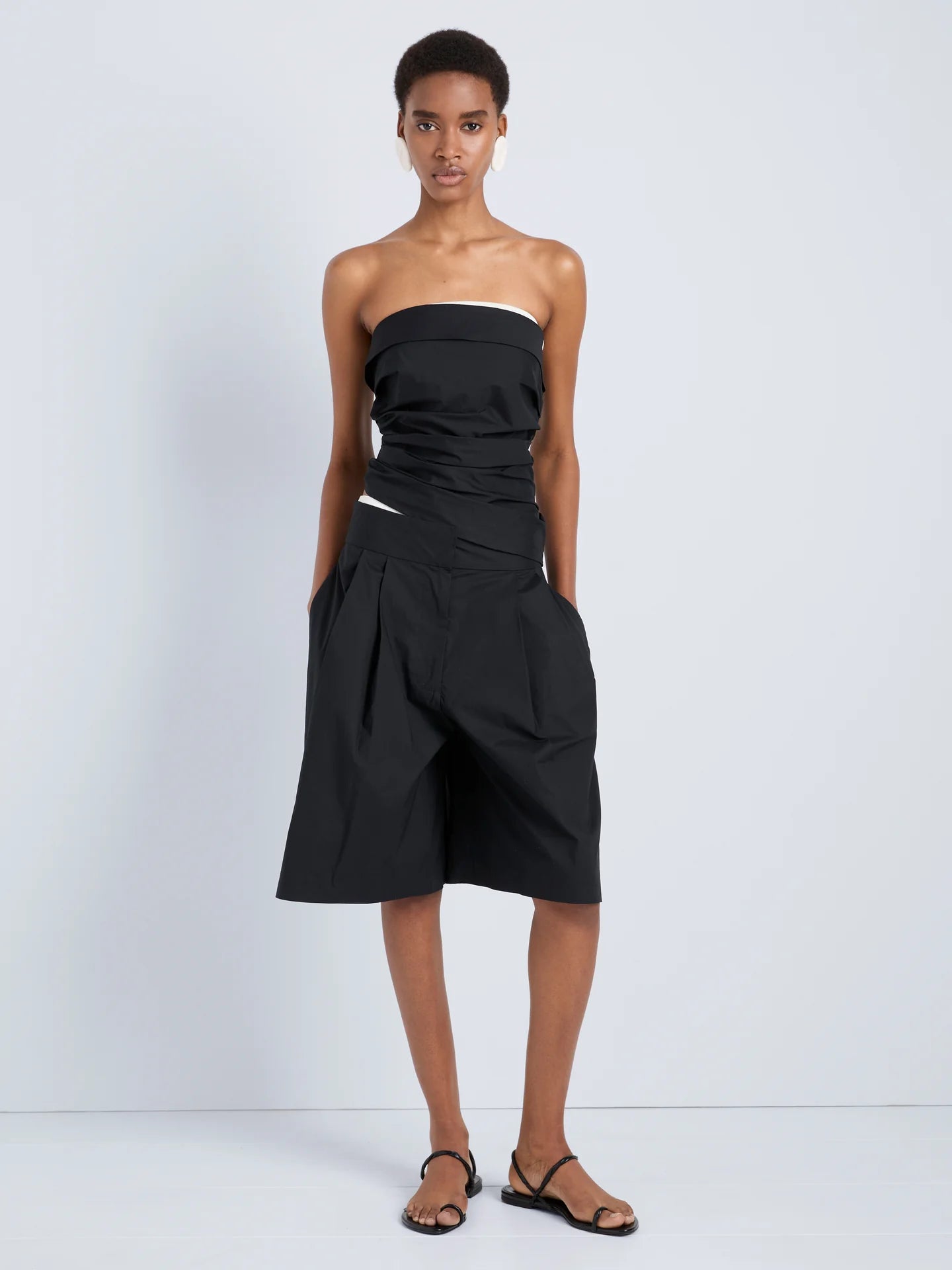 Woman wearing a black strapless dress on a white background