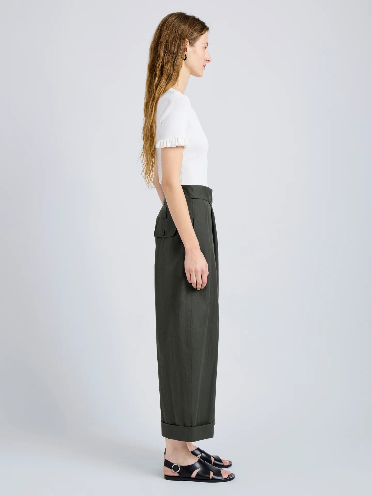 Person wearing a white top and dark green wide-leg pants on a light gray background