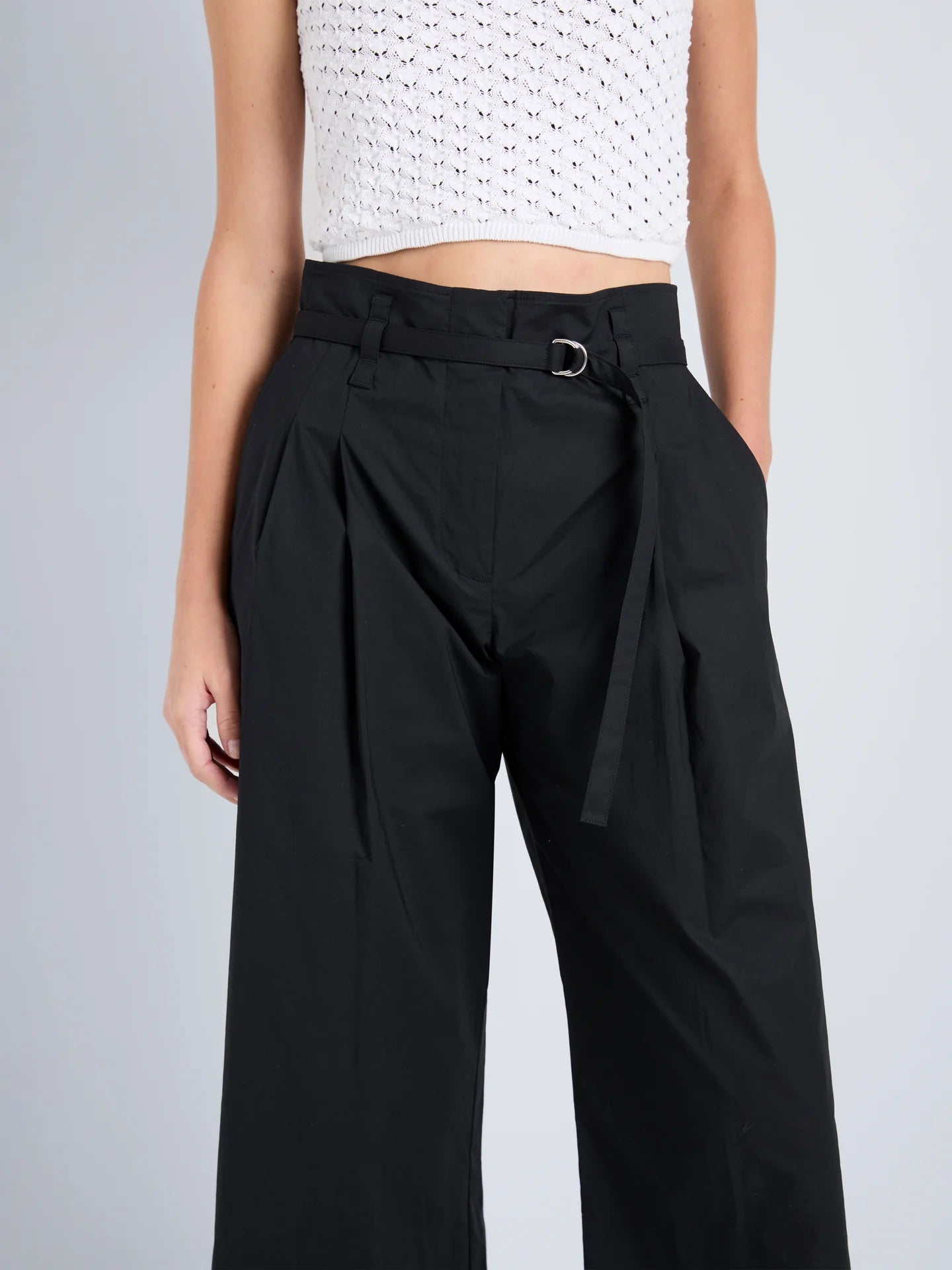 Person wearing black wide-leg pants with a white top on a gray background