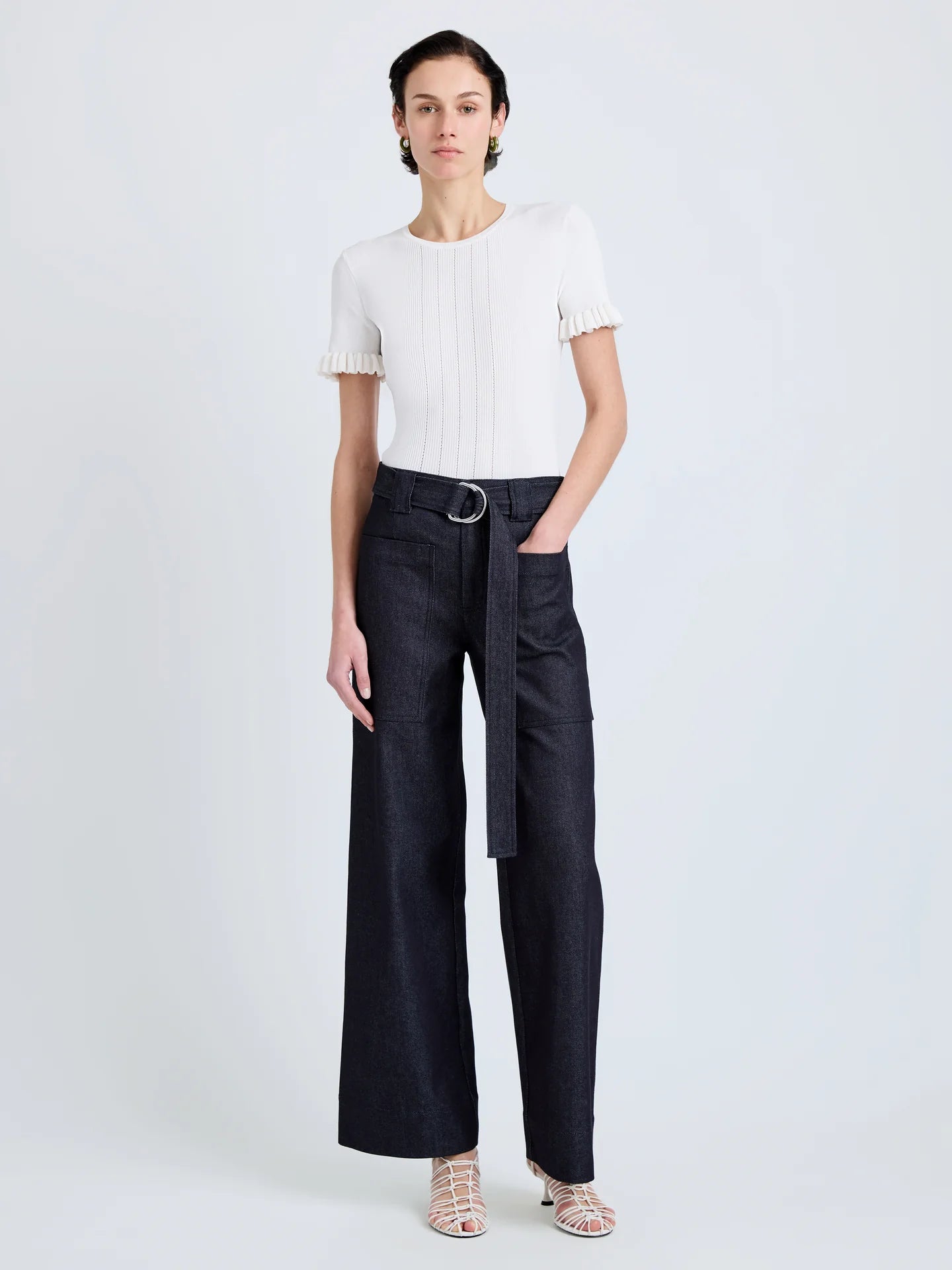Woman wearing a white top and black high-waisted pants on a light gray background