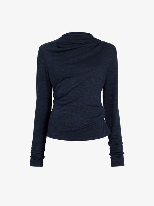 A light gray studio background with a dark navy long-sleeve draped top