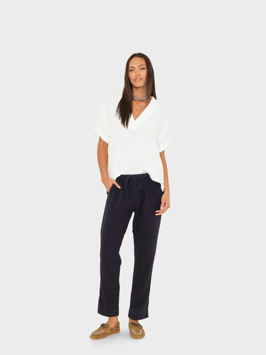Woman wearing a white top and dark pants on a white background