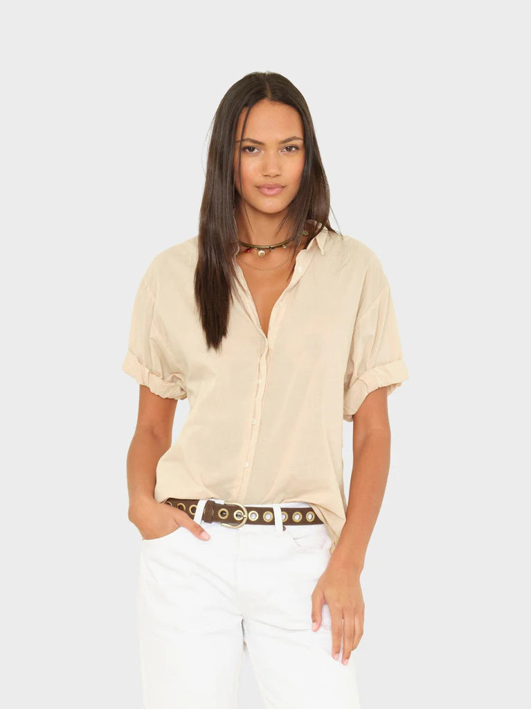 Woman wearing a beige shirt and white pants on a beige background