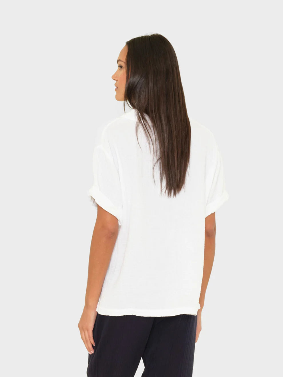 Woman wearing a white blouse and dark pants on a plain background