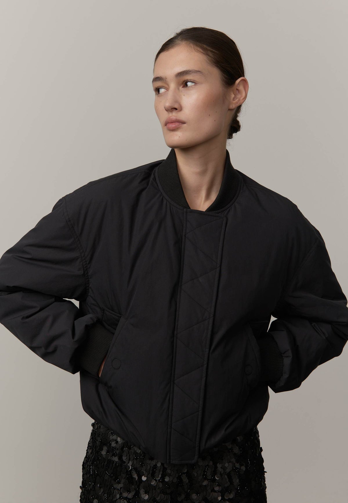 Person wearing a black jacket against a plain background