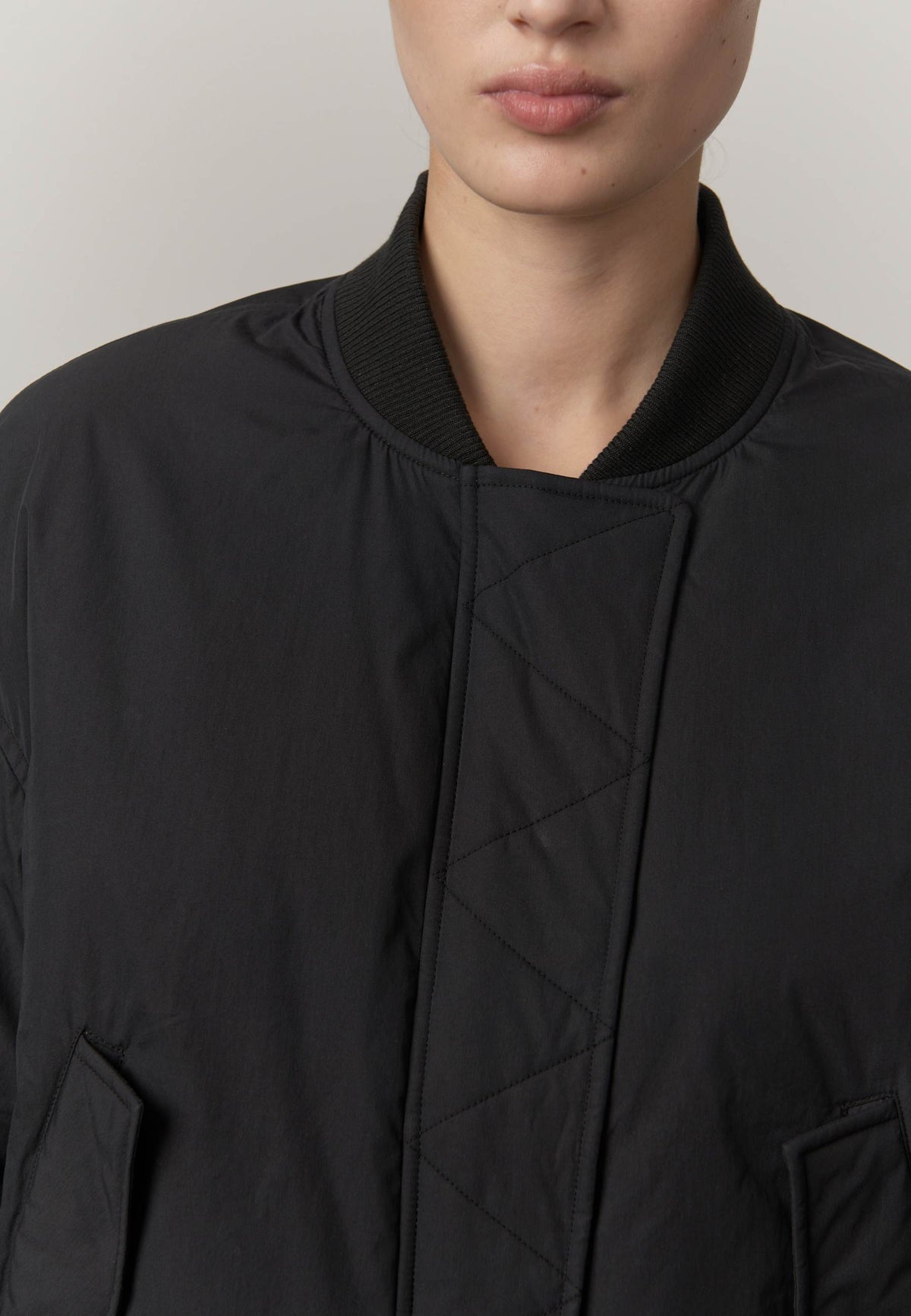 Close-up of a person wearing a black jacket with a plain background