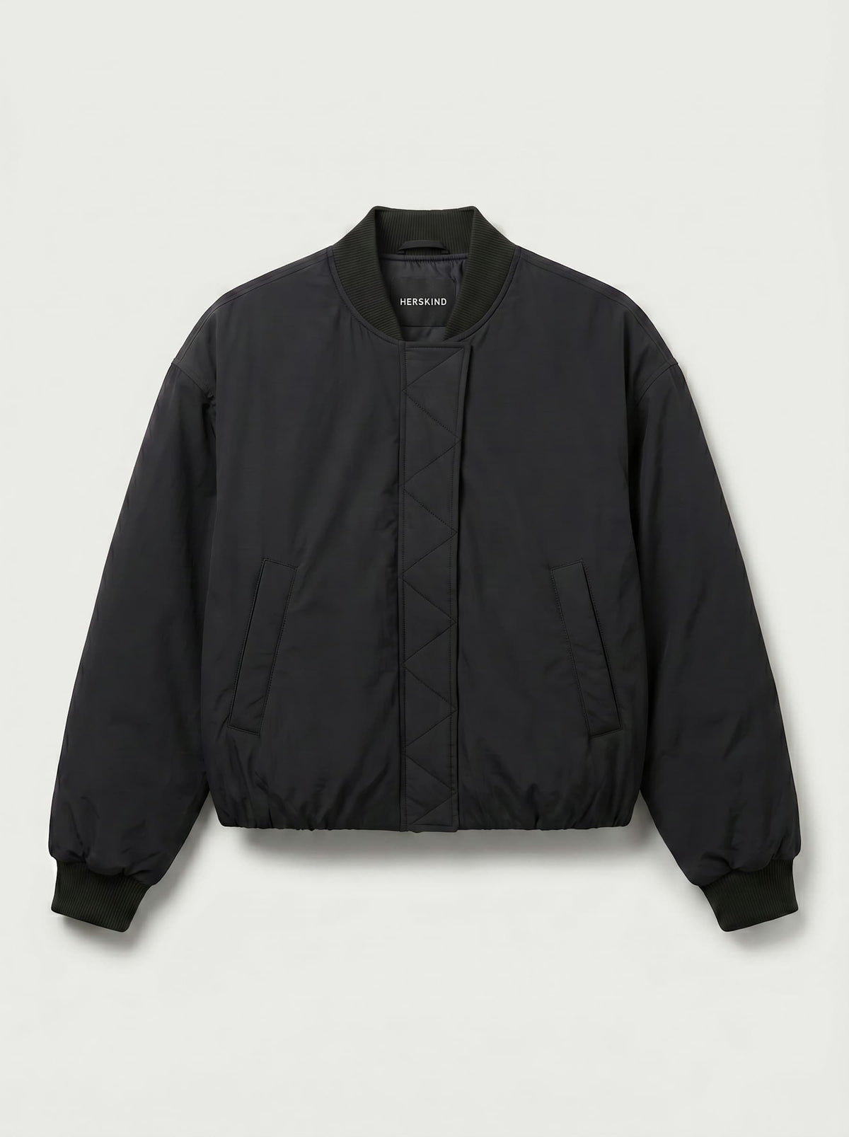 A black quilted bomber jacket with a ribbed collar, cuffs, and hem, featuring a diamond-quilted front panel and side pockets, shown against a light gray background.
