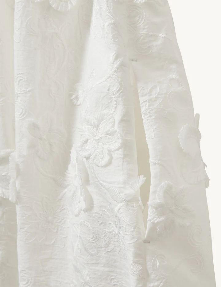 Close-up of a textured white fabric with floral patterns on a white background
