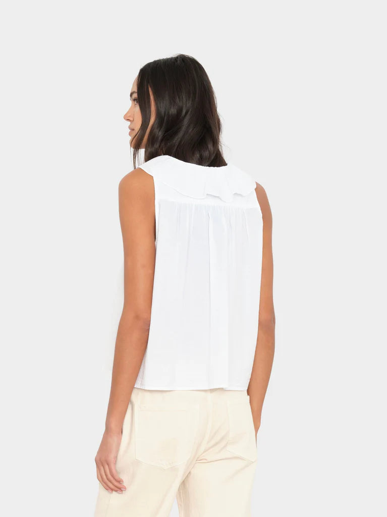 Woman wearing a white sleeveless top and beige pants on a white background